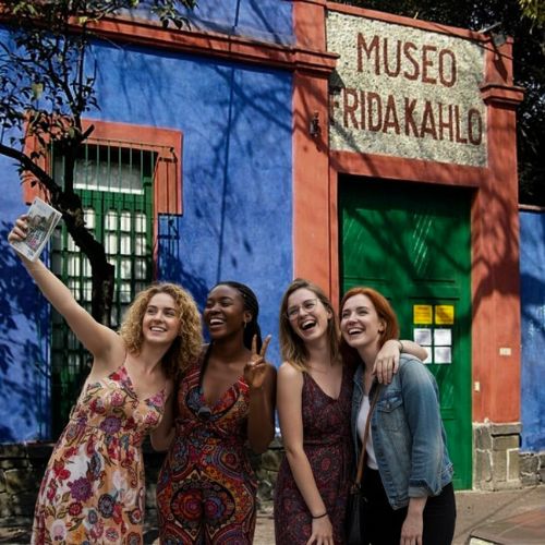 Small group of travelers shooting a selfie in front of Frida Kahlo's Casa Azul in Coyoacan