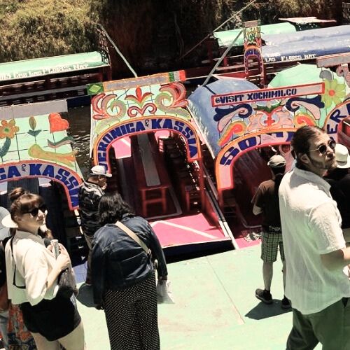 Colorful trajinera boats at Xochimilco canals with travelers getting ready for a private boat tour.