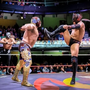 Professional Mexican wrestlers (luchadores) performing a high-energy match at Arena Mexico.