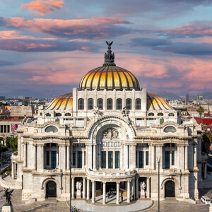 Aerial view of the Palacio de Bellas Artes with its golden dome during sunset in Mexico City's historic center.