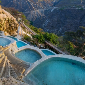 Natural thermal pools at Grutas de Tolantongo during sunrise, surrounded by canyon mountains in Hidalgo, Mexico.